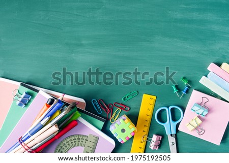 Back to school background. School supplies, pens, pencils, notebooks, ruler, scissors on a  against the background of a green school board, copy space, top view. 
