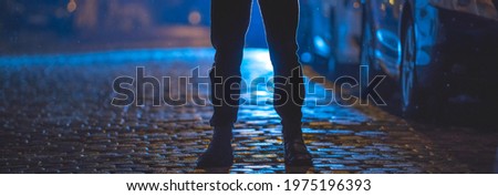 The man stand on the wet road. Evening night time. Telephoto lens shot