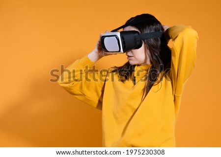 young woman with a virtual reality device on a yellow background.