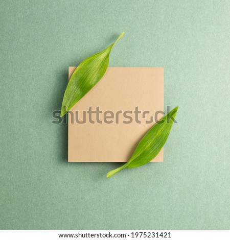 Kraft memo pad with green leaf on green background. top view, copy space