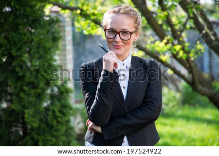 Girl in a business suit with glasses a pen looks in the picture. portrait