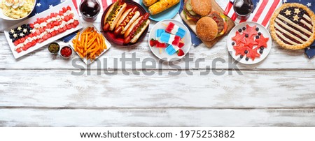 Fourth of July, patriotic, American themed food. Above view top border on a white wood banner background. Copy space.