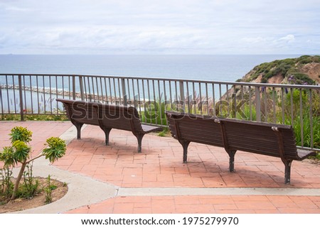 Two wood benches by the fence with beach background. Peaceful scenery in California. Vacation time. Summer views.