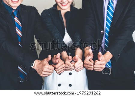 Many happy business people make thumbs up sign join hands together with joy and success. Company employee celebrate after successful work project. Corporate partnership and achievement concept.