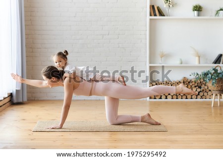 Young woman in light pink outfitt practice yoga,staying in plank Side view of slender woman doing yoga in Balancing Table asana while stretching body and practicing mindfulness,fit family yoga in room Royalty-Free Stock Photo #1975295492