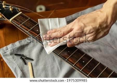Cleaning guitar fretboard with wet wipes made for guitar Royalty-Free Stock Photo #1975309985