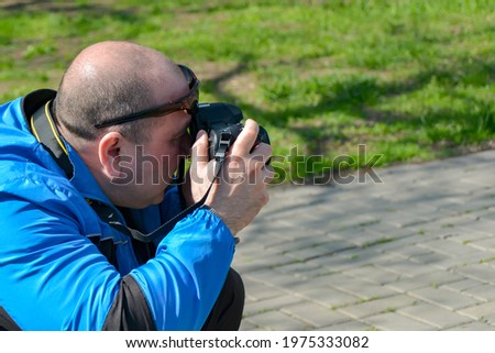 A man looks through the captured images, photographed with a SLR camera in the park.