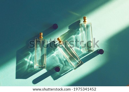 three Glass bottles on a light blue background with a shade from the sun. Summer marine unisex perfume concept Royalty-Free Stock Photo #1975341452