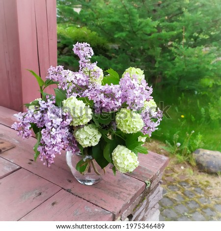 Bouquet of lilac and viburnum Buldenezh on a wooden surface. 