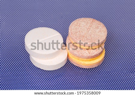 Different effervescent tablets of pharmaceutical product on a blue surface, close-up in selective focus
