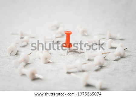 standing red thumbtack among blurred  white thumbtacks on grunge grey background , for outstanding leader, winner , strongest ,success , the best things or idea, winner among loosen concept Royalty-Free Stock Photo #1975365074