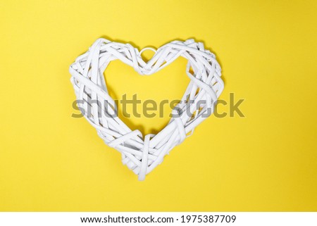 White rattan heart on yellow background. a symbol of love and congratulations on Valentines Day. flatley, copy space