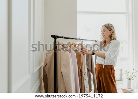 Fashion stylist sorting the clothing rack Royalty-Free Stock Photo #1975411172