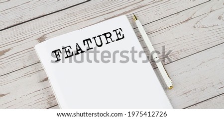 Notepad with text FEATURE . White background. Business