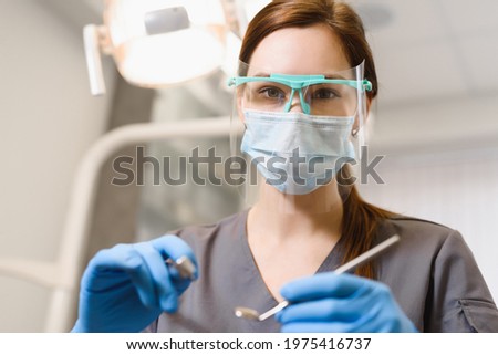 Female dentist at work in the clinic. A doctor wearing a face shield conducts a dental examination and treatment. First person shooting close-up