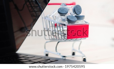 Multiple transparent bottles of vaccine With gray cover Placed in a small red shopping cart There is a notebook placed near the concept of vaccine ordering, vaccine reservation.