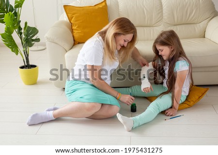 Mother and daughter drawing picture on bandage using paints. Play therapy concept.