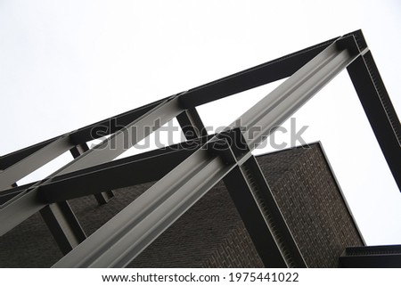 Low angle close-up fragment of industrial building with lift shaft and perforated panels. Modern industry and minimal architecture background with modular structure of glass and metal framework.  Royalty-Free Stock Photo #1975441022