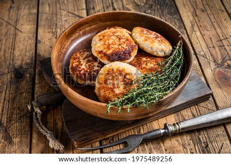 Roasted fish cutlets or patty in a wooden plate. wooden background. Top view