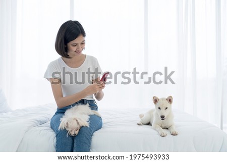 Young Asian women take photo with mobile phone. Young Asian women and girl were in bed with a dog. Girl and white Hokkaido inu dog and Maltese dog.