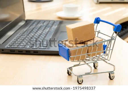 metal chrome cart with boxes on the background of a black laptop and a coffee cup on a working wooden table. selective focus