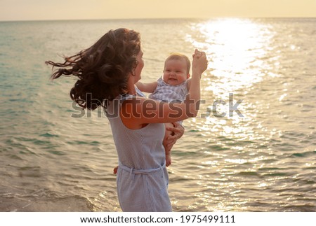 Mother holding daughter in the beach. Woman with kid resting with fun in the Sandy seashore 