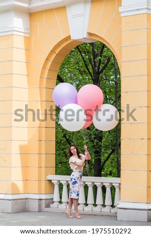 Model with a cloud of colorful balloons in the city.