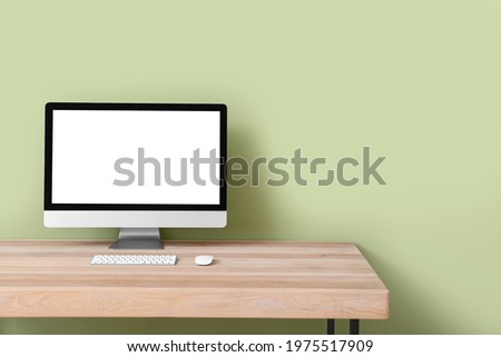 Modern PC monitor on table near color wall