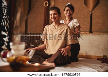 Thai massagist and her patient smiling to camera Royalty-Free Stock Photo #1975530593
