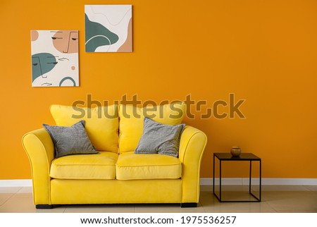Stylish interior of living room with colorful sofa, table and pictures