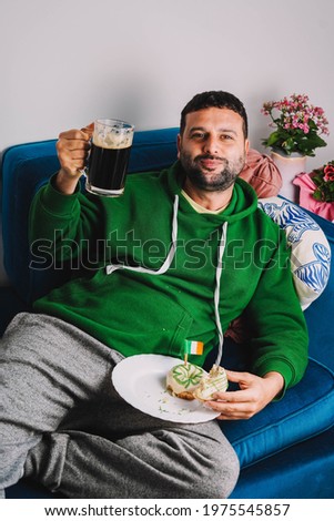 Irish man eating dunuts with Irish stout to celebrate st patricks day

