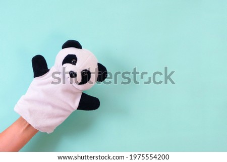 Puppet theater toys on a hand on a turquoise background. Childrens entertainment concept. panda