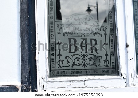 close up of sign for a  Bar etched on window outside a public house in springtime with a reflection of a street lamp