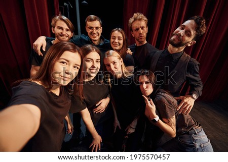 Making selfie. Group of actors in dark colored clothes on rehearsal in the theater. Royalty-Free Stock Photo #1975570457