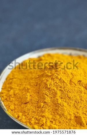 Close up picture of turmeric powder in a bowl, shallow depth of field, space for text.
