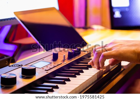 male musician hand playing midi keyboard for arranging music on laptop computer. music production technology concept