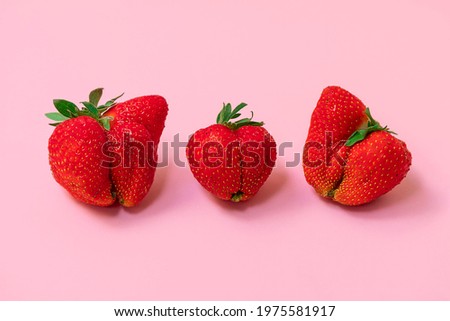 Large ugly strawberries on soft pink background. Ugly food concept Royalty-Free Stock Photo #1975581917