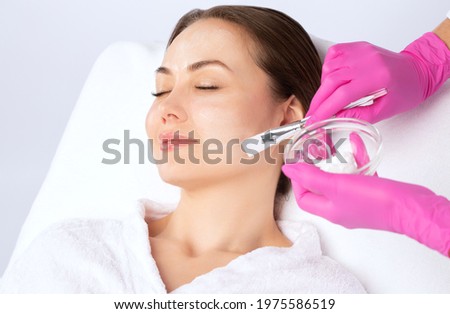 Beautician makes a face mask of a woman to rejuvenate the skin. Cosmetology treatment of problem skin on the face and body.