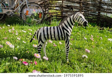 Summer cottage for outdoor recreation. Crafts from a tree. Zebra, horse made of wood on a background of spring grass.