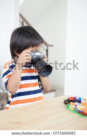 Asian kid with camera. Child learning how to take photograph.