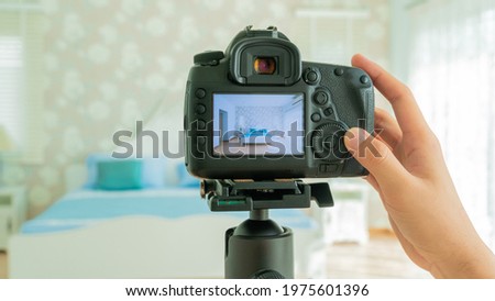 Camera on a tripod in bedroom interior, Professional DSLR digital camera, selective focus, Horizontal orientation, copy space, Photographer hands holding professional camera.