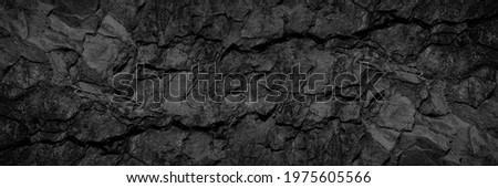 Volumetric rock texture with cracks. Black stone background with copy space for design. Wide banner.