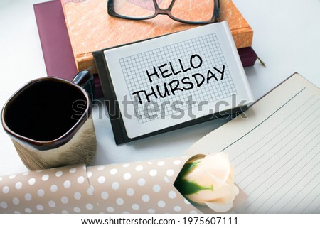Office table with supply notepad with text Hello Thursday flower and coffe cup. Can be use as concept photo Royalty-Free Stock Photo #1975607111