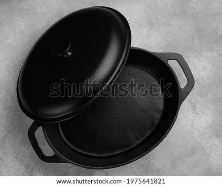 Cast iron pot with lid. A casserole pot On a gray concrete background. Empty clean black Castiron cooking utensils. Top view, copy space