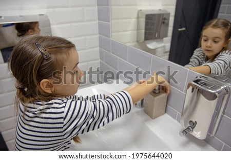 Little girl uses liquid soap to wash her hands. Hygiene and cleanliness in a coronavirus environment.