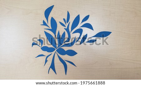 Blue foam cut-outs arranged and photographed on a plastic table with uneven overhead fluorescent and incandescent lighting.
