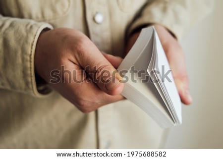 White note paper in the hands of a man. Blank letterhead close up. Mockup. Office worker with a stack of note paper. Blank space for message or invitation on paper