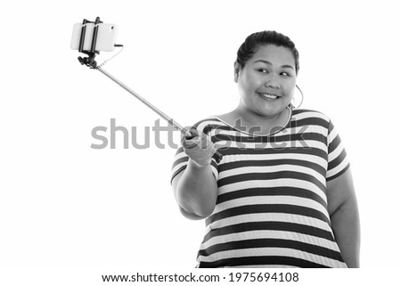 Studio shot of young beautiful overweight Asian woman isolated against white background in black and white