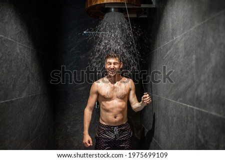 Man hardening with bucket of ice cold water after hot sauna, healthy lifestyle and cold training concept. Wellness and spa. Royalty-Free Stock Photo #1975699109