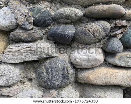 A wall of nautical round, sandstone and other gray, black and white stones as a background